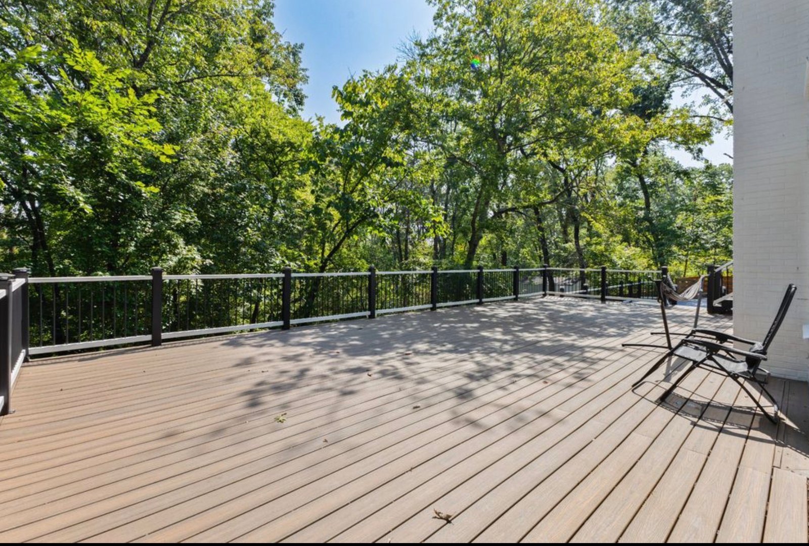 Custom composite deck installation in Nashville, TN with black railing and wooded backyard view